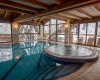 Wewnętrzny basen z jacuzzi i zimowym widokiem na zaśnieżone drzewa.