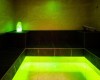 Sauna parowa z czarnymi ławkami i zielonym oświetleniem.