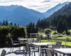 Taras z zewnętrznymi stolikami i widokiem na góry.