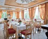 Przestronna restauracja z eleganckim drewnianym sufitem i czerwono-żółtymi zasłonami.