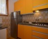Mała kuchnia z pomarańczowymi szafkami i retro kafelkami.