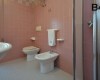 Łazienka z różowymi kafelkami, toaletą, bidetem i umywalką.