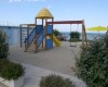 Plac zabaw z zjeżdżalnią i huśtawką blisko morza.
