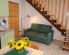 Salon z kanapą, schodami i stołem jadalnym z wazonem słoneczników.