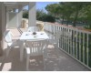 Przestronny balkon z plastikowym stołem, czterema krzesłami i filiżankami.