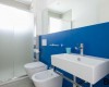 Nowoczesna łazienka z niebieską ścianą, umywalką, toaletą i bidetem.