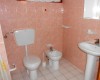 Łazienka z toaletą, bidetem i umywalką, wyłożona różowymi kafelkami.