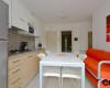 Nowoczesna kuchnia z białym stołem i pomarańczową sofą.