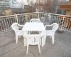 Biały plastikowy stół jadalniany z czterema krzesłami na tarasie.