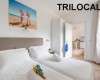 Jasny pokój z dwoma łóżkami, plakatem na ścianie i napisem TRILOCALE.