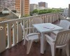 Plastikowy stół i krzesła na balkonie z widokiem na zabudowę miejską.