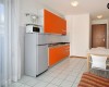 Nowoczesna kuchnia z pomarańczowymi szafkami, lodówką i stołem jadalnym.