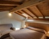 Sypialnia na poddaszu z drewnianym sufitem, łóżkiem małżeńskim i sofą.