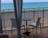 Widok na morze z balkonu z dwoma krzesłami i stołem.