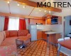Wnętrze domu mobilnego z aneksem kuchennym, zestawem wypoczynkowym i napisem M40 TREND.