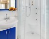 Nowoczesna łazienka z niebieską szafką i białą kabiną prysznicową.
