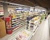 Wnętrze supermarketu z regałami pełnymi jedzenia i napojów.