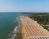 Długa piaszczysta plaża z rzędami kolorowych parasoli nad morzem.