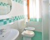Łazienka z umywalką, toaletą, bidetem i prysznicem z turkusowymi kafelkami.