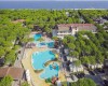 Widok z lotu ptaka na ośrodek wypoczynkowy z basenami otoczonymi drzewami i blisko położonym morzem.