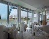 Nowoczesna restauracja z białymi obrusami i dużymi oknami z widokiem na zewnątrz.