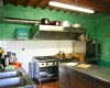 Kuchnia z metalowymi meblami, kuchenką i zielonymi ścianami.