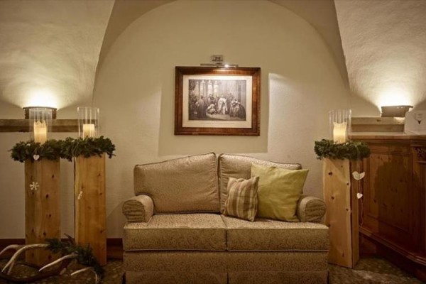 Sofa z poduszkami, obraz na ścianie i świece na drewnianych stojakach w rustykalnym pokoju.