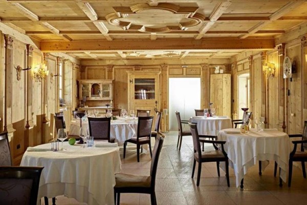 Restauracja z drewnianymi panelami i okrągłymi stolami z obrusami.