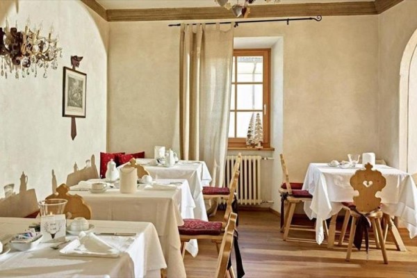 Restauracja z rustykalnymi stołami nakrytymi białymi obrusami.