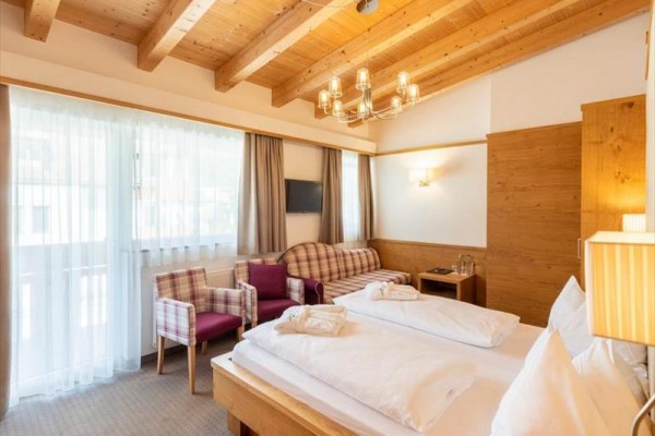 Pokój hotelowy z drewnianym sufitem, podwójnym łóżkiem, kanapą i telewizorem.