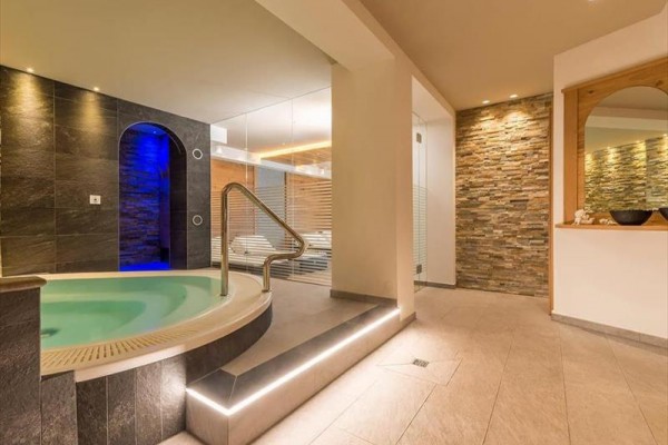 Strefa wellness z jacuzzi i miejscem do relaksu w jasnym nowoczesnym wnętrzu.
