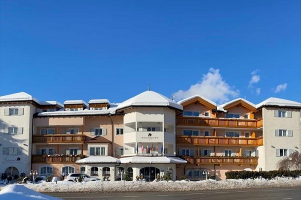 Duży hotel z balkonami w zimowy dzień na zaśnieżonej ulicy i niebieskim niebie.