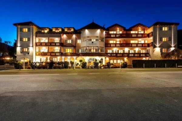 Budynek hotelu nocą z zapalonymi światłami i niebieskim niebem.