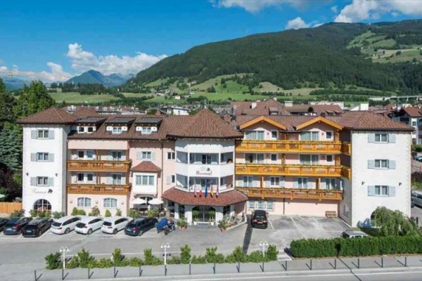 Hotel otoczony górami i zaparkowanymi samochodami.