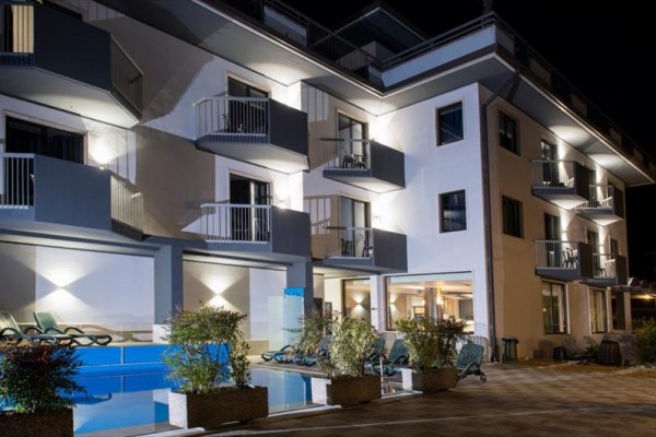 Nowoczesny hotel z tarasami oświetlony nocą.