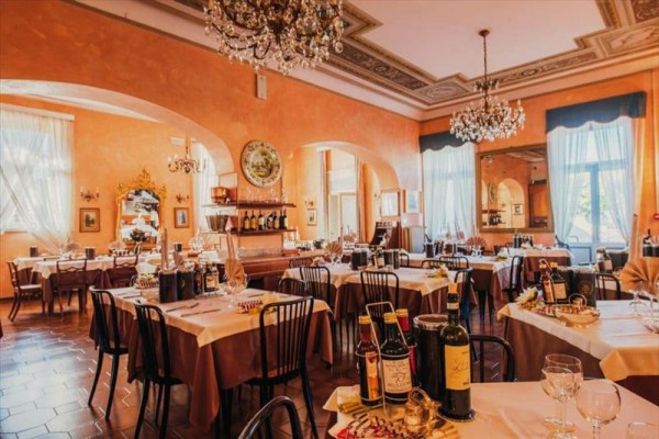 Elegancka restauracja z nakrytymi stołami i żyrandolami na suficie.