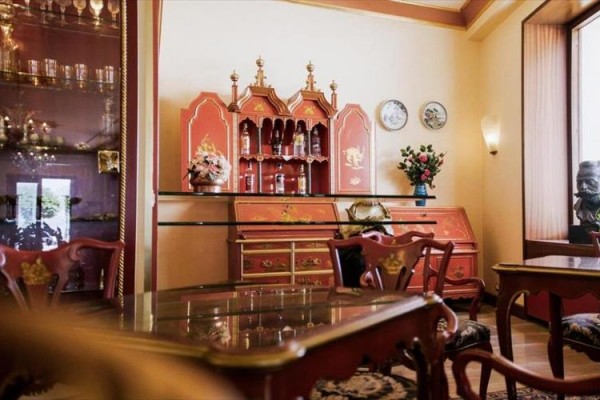 Eleganckie wnętrze z czerwonymi meblami, szklanymi witrynami i dekoracyjnymi przedmiotami.