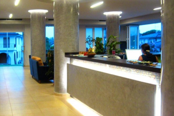 Luksusowa recepcja hotelowa z nowoczesnym oświetleniem i hallem, gdzie przy stole siedzi osoba.