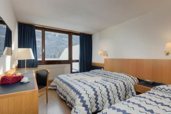 Pokój hotelowy z dwoma łóżkami i widokiem na ośnieżone góry.