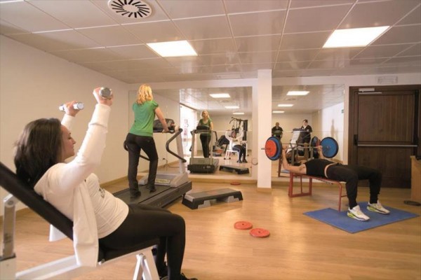Ludzie ćwiczą na siłowni z różnym sprzętem fitness.