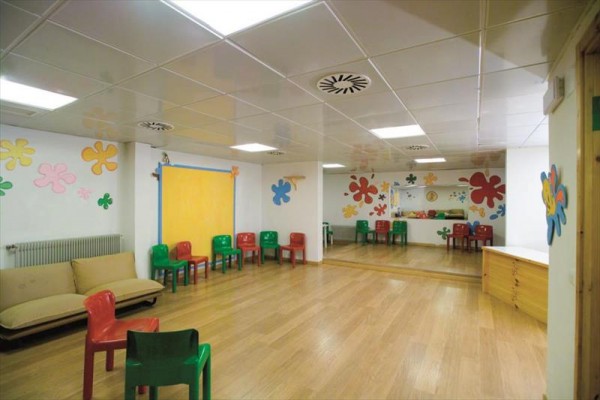 Sala zabaw dla dzieci z kolorowymi krzesłami i dekoracjami na ścianach.