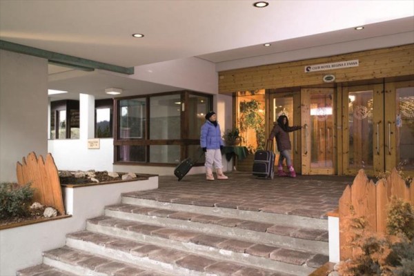 Dwoje dzieci z walizkami wchodzi do budynku hotelu.