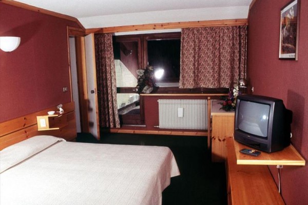 Pokój hotelowy z łóżkiem, telewizorem i balkonem.