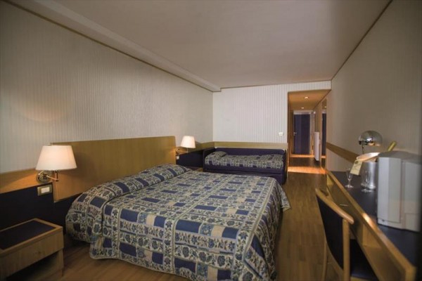 Pokój hotelowy z dwoma łóżkami, stołem i lampką.