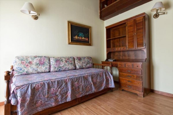 Sofa z kwiecistym narzutem obok drewnianej szafy i lampy.