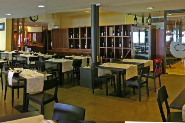 Przestronna restauracja ze stołami przykrytymi jasnobeżowymi obrusami.