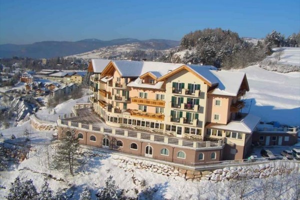 Duży hotel z kolorowymi fasadami w zaśnieżonym górskim krajobrazie.
