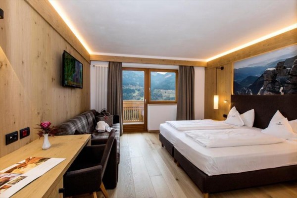 Nowoczesny pokój hotelowy z drewnianymi meblami i widokiem na góry.