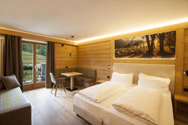 Nowoczesny pokój hotelowy z drewnianym wykończeniem, łóżkiem i małą jadalnią.