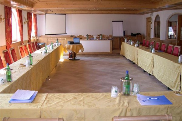 Sala konferencyjna z rozstawionymi stołami, krzesłami i projektorem.